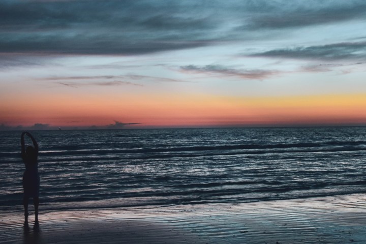 a sunset over a beach next to the ocean